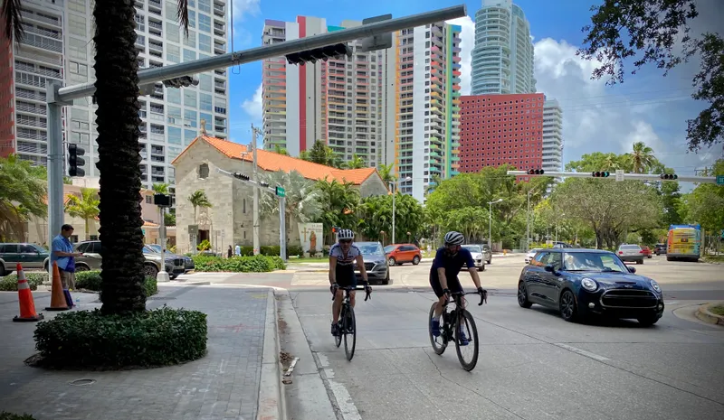 Two cyclists riding in the street on a sunny day in Brickell